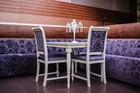 Modern restaurant in purple color style with nice chairs and wood white tablesの写真素材