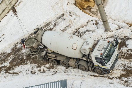 Concrete mixer truck pouring liquid concrete into the tower crane bucket at the construction site...