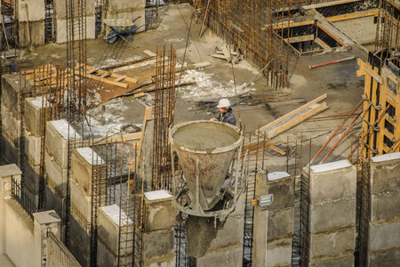 Tower crane bucket full of concrete liquid is delivering to the site.