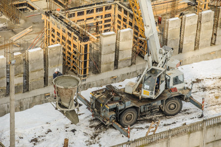 Tower crane bucket full of concrete liquid is delivering to the site. 