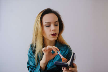 Portrait of sexy smiling happy caucasian young woman applying foundation blusher with makeup brushの写真素材