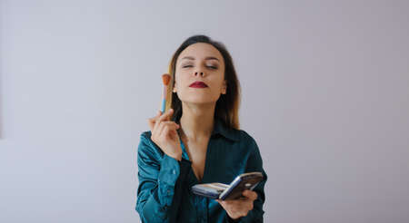 Portrait of sexy smiling happy caucasian young woman applying foundation blusher with makeup brushの写真素材