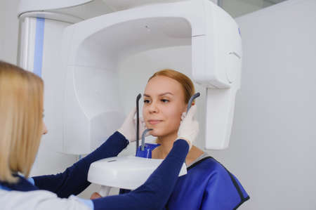 A woman patient make an digital X-ray of the oral cavity and dentist is positions her.の写真素材