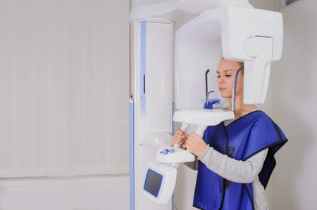Close up of woman patient doing panoramic teeth x-ray in dental clinic in protective clothes....