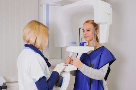 A woman patient make an digital X-ray of the oral cavity and dentist is positions her.の写真素材