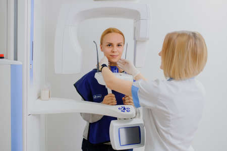 A woman patient make an digital X-ray of the oral cavity and dentist is positions her.の写真素材