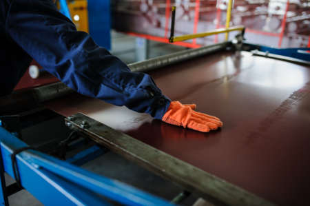 industrial worker spray on metal sheet profiling machine at manufacturing factoryの写真素材