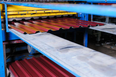 Metal tile manufacturing factory. Steel sheet metal roll profiling forming machine with rolls in working process.の写真素材