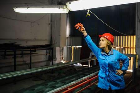 beautiful woman in red safety helmet work as industrial worker at metal sheet profiling mechine at manufacturing factoryの写真素材