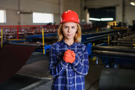 Portret of nice beautiful woman in red safety helmet at metal tile roof manufacturing factoryの写真素材