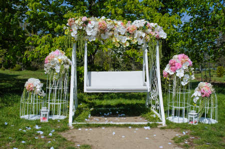 Wedding composition decoration in old vintage romantic style with white metal cages and nice swingの写真素材