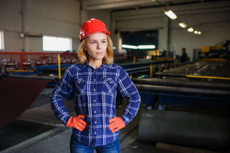 Portret of nice beautiful woman in red safety helmet at metal tile roof manufacturing factoryの写真素材