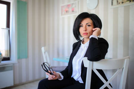 portrait of beautiful  business lady (woman/girl) dressed in black suit in a vintage cafe/officeの写真素材