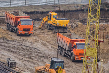 Industrial truck loader excavator moving earth and unloading into a dumper truck and bulldozer is moving groundの写真素材