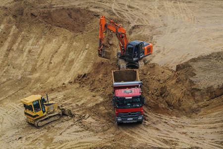 Industrial truck loader excavator moving earth and unloading into a dumper truck and bulldozer is moving groundの写真素材