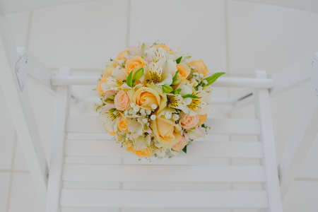 Beautiful fresh spring tender wedding bouquet of cream roses and eustoma flowers on wood white chairの写真素材