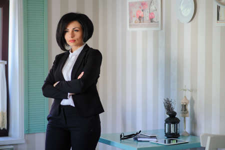 portrait of beautiful  business lady (woman/girl) dressed in black suit in a vintage cafe/officeの写真素材