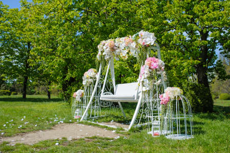 Wedding composition decoration in old vintage romantic style with white metal cages and nice swingの写真素材