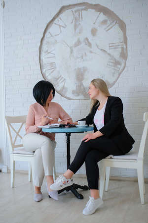 two business women have a meeting in a vintage cafe/office and working on a tablet ( portable compute )の写真素材