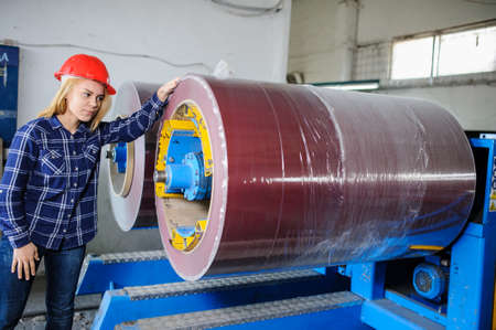 beautiful woman standing near metal coil at metal tile manufacturing factory and prepare it for profiling processの写真素材