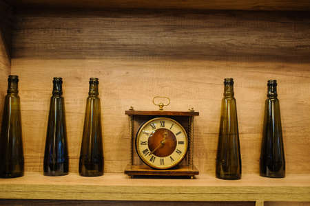 vintage composition of old wine bottle and clock on rustic dark wood background.の写真素材