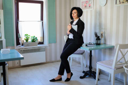 beautiful  business lady (woman/girl) dressed in black suit sitting in a vintage cafe/officeの写真素材