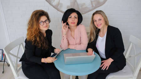 three business women have a meeting in a vintage cafe/office and working on a notebook ( portable compute ).の写真素材