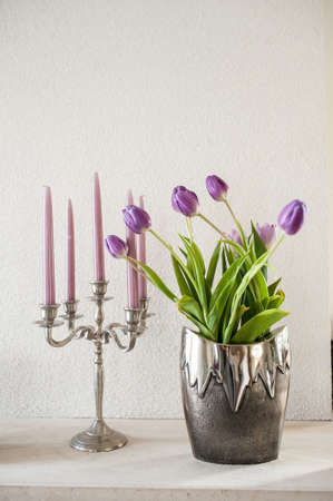 vintage decoration. violet tulips in silver metal vase and violet candles in metal candlestickの写真素材