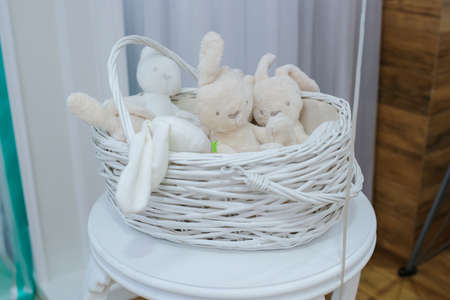 Composition from white fluffy soft stuffed toy rabbits bunny sitting in the basketの写真素材