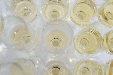 Composition from rows of glasses filled with champagne that are lined up ready to be served on a...
