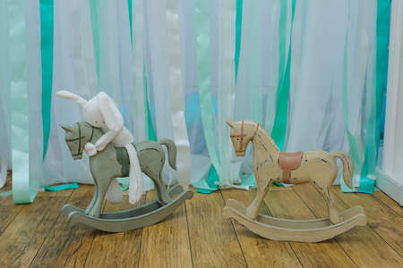 Composition from white fluffy soft stuffed toy rabbit bunny sitting on the wood horseの写真素材