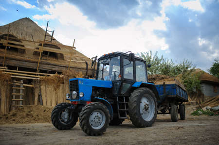 Tractor in a old village with nice house with reed roofの写真素材