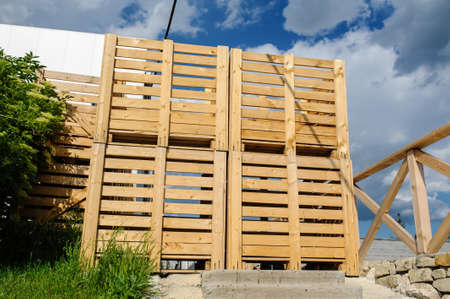 Wood pallets arranged in row, and blue sky behindの写真素材