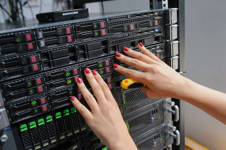Close-up of young woman engineer It with a screwdriver in a server room in the data center and fix the problem with conectionの写真素材