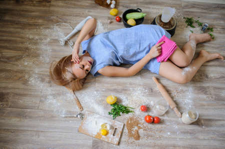 Concept: top view of desperate housewife lying on the floor in her kitchen with flour on her faceの写真素材