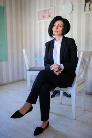 beautiful  business lady (woman/girl) dressed in black suit sitting in a vintage cafe/officeの写真素材