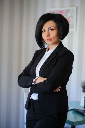 portrait of beautiful  business lady (woman/girl) dressed in black suit in a vintage cafe/officeの写真素材