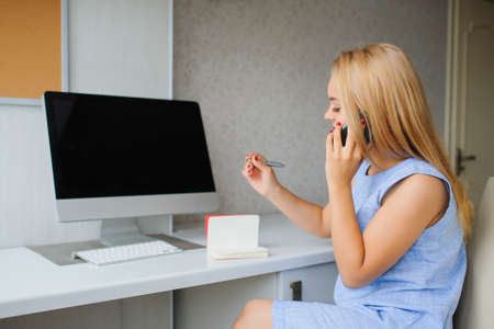 Serious and angry young woman in blue dress working on a pc in her officeの写真素材