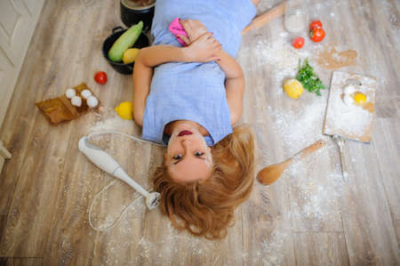 Concept: top view of desperate housewife lying on the floor in her kitchen with flour on her faceの写真素材