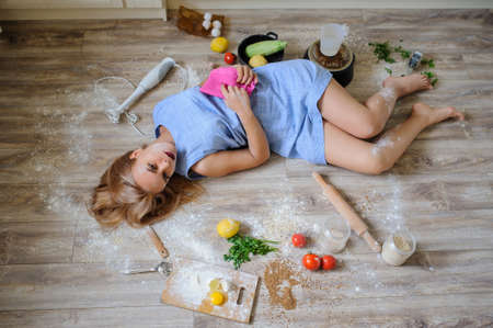 Concept: top view of desperate housewife lying on the floor in her kitchen with flour on her faceの写真素材