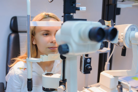 Portret of young beautiful patient in an ophthalmologic clinic doing biomicroscopy with slit lamp...