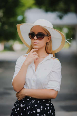 young beautiful sexy woman with white hat and glasses outdoor on green backgroundの写真素材