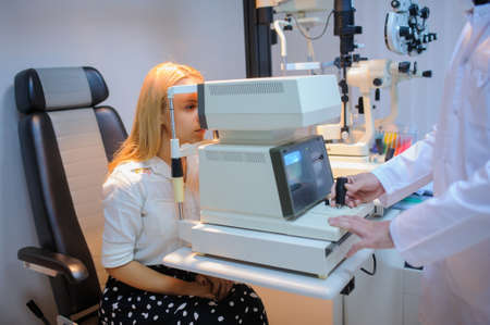 Eye Doctor/optometrist/ophthalmologist examinating a young patient using a non-mydriatic retinal cameraの写真素材