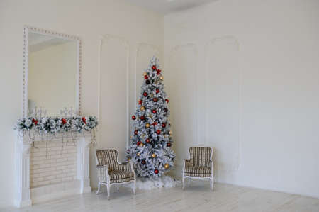 Modern style interior of fireplace with christmas tree, two vintage chairs in white colour, mirror on fireplaceの写真素材