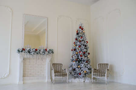 Modern style interior of fireplace with christmas tree, two vintage chairs in white colour, mirror on fireplaceの写真素材