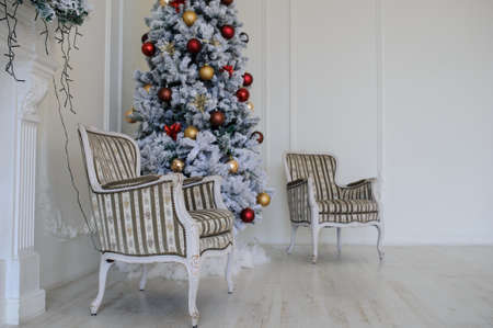 Modern style interior of fireplace with christmas tree, two vintage chairs in white colour, mirror on fireplaceの写真素材