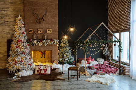 Vintage style interior of fireplace with christmas tree, vintage chair, artificial snow, beautiful bedの写真素材