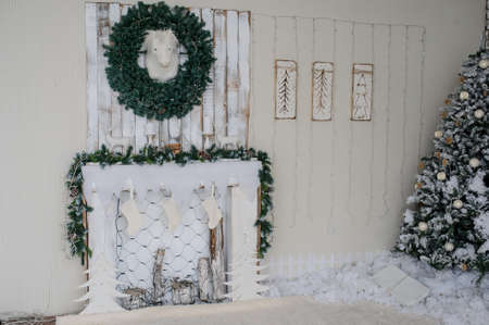 Vintage style interior of fireplace with christmas tree, vintage chair in white colour, and artificial snowの写真素材