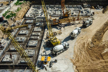 white mixers and yellow crane at the construction site of a building in summer daysの写真素材