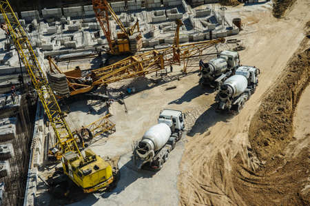 white mixers and yellow crane at the construction site of a building in summer daysの写真素材